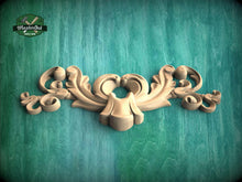 Load image into Gallery viewer, A decorative wooden carving with intricate scrollwork is displayed against a green textured background.