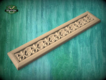 Load image into Gallery viewer, A decorative wooden panel with an intricate floral design, resting on a green wooden surface.