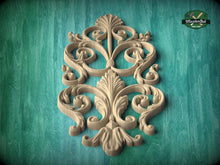 Load image into Gallery viewer, an ornate, carved wooden design with intricate scrollwork and floral elements, set against a teal background.