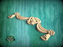 Load image into Gallery viewer, A decorative wooden carving with floral and floral-like elements is displayed against a green background.