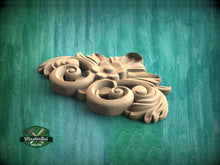 Load image into Gallery viewer, A decorative wooden carving with intricate scrollwork and floral elements is displayed against a green textured background.