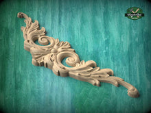 Load image into Gallery viewer, A decorative wooden carving with intricate scrollwork and floral elements is displayed against a green textured background.