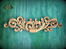 Load image into Gallery viewer, a wooden carving of a scroll on a green background