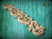 Load image into Gallery viewer, A decorative wooden carving with intricate scrollwork and floral patterns is displayed against a teal background.