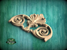 Load image into Gallery viewer, A decorative wooden carving with intricate scrollwork is displayed against a green background.