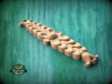 Load image into Gallery viewer, A wooden carving of a flower-like design is displayed against a green background.