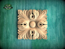 Load image into Gallery viewer, a square, ornate, carved wooden piece with a floral design, placed on a green wooden surface.