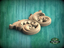 Load image into Gallery viewer, A wooden carving of a stylized leaf or flower design is displayed against a green background.