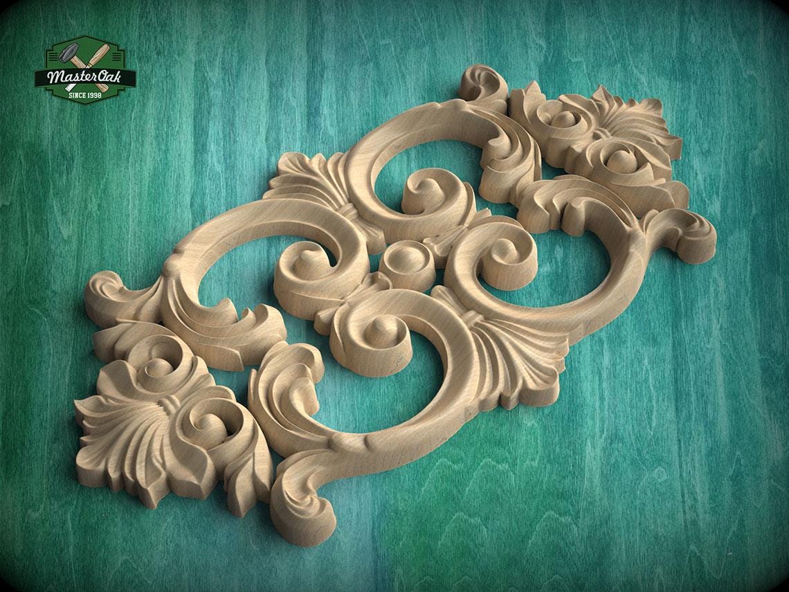 a carved wooden piece with intricate scrollwork and floral designs, set against a green background.
