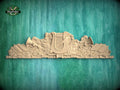 A wooden carving of a harp and musical instruments is displayed against a green wooden background.