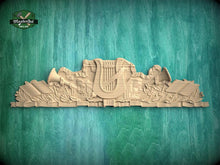 Load image into Gallery viewer, A wooden carving of a harp and musical instruments is displayed against a green wooden background.
