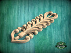 A decorative wooden carving with a leaf-like design is displayed against a green background.