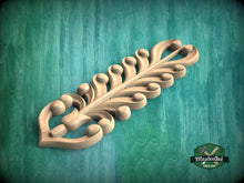 Load image into Gallery viewer, A decorative wooden carving with a leaf-like design is displayed against a green background.
