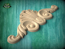 Load image into Gallery viewer, A wooden carving of a stylized floral design is displayed against a teal background.
