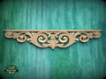 a decorative wooden carving on a green wooden surface.