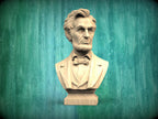 A bust of Abraham Lincoln, a famous American president, is displayed against a green wooden background.