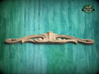 A decorative wooden mold or carving is displayed against a green textured background.