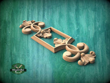 Load image into Gallery viewer, A wooden carving of a decorative floral design is displayed against a green background.
