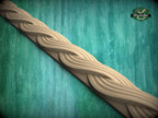 A decorative wooden molding with a swirling, braided pattern is displayed against a green textured background.