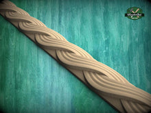 Load image into Gallery viewer, A decorative wooden molding with a swirling, braided pattern is displayed against a green textured background.
