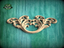 Load image into Gallery viewer, A decorative wooden carving with intricate scrollwork is displayed against a green wooden background.
