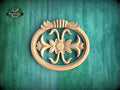 A wooden ornamental piece with a floral design is displayed against a green background.
