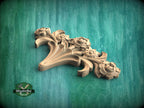 A wooden carving of a flower with intricate details is displayed against a green background.