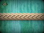A close-up view of a braided wooden object, possibly a piece of furniture or a decorative item, set against a textured green background.