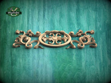 Load image into Gallery viewer, A decorative wooden carving with intricate floral and scrollwork designs is displayed against a green textured background.
