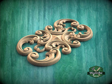 Load image into Gallery viewer, A decorative wooden carving with intricate swirls and curves is displayed against a green background.

