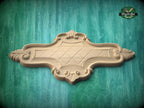 a wooden decorative piece with an ornate design, placed against a green background.