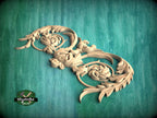 A decorative wooden carving with intricate floral and leaf-like patterns is displayed against a green background.