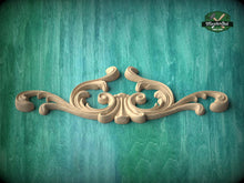 Load image into Gallery viewer, A decorative wooden carving in the shape of a scroll adorns a turquoise background.
