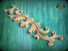 Load image into Gallery viewer, A decorative wooden carving with intricate scrollwork is displayed against a green background.
