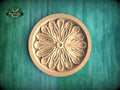 A wooden ornate flower design in a round bowl, set against a green background.