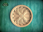 A wooden ornate flower design in a round bowl, set against a green background.