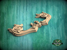 Load image into Gallery viewer, A decorative wooden carving with intricate floral and leaf-like patterns is displayed against a green textured background.
