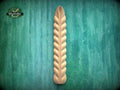 A wooden decorative element with a ribbed texture is displayed against a green textured background.