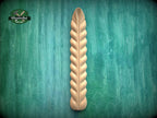 A wooden decorative element with a ribbed texture is displayed against a green textured background.