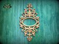 an ornate, carved wooden frame with an oval shape in the center, set against a green background.