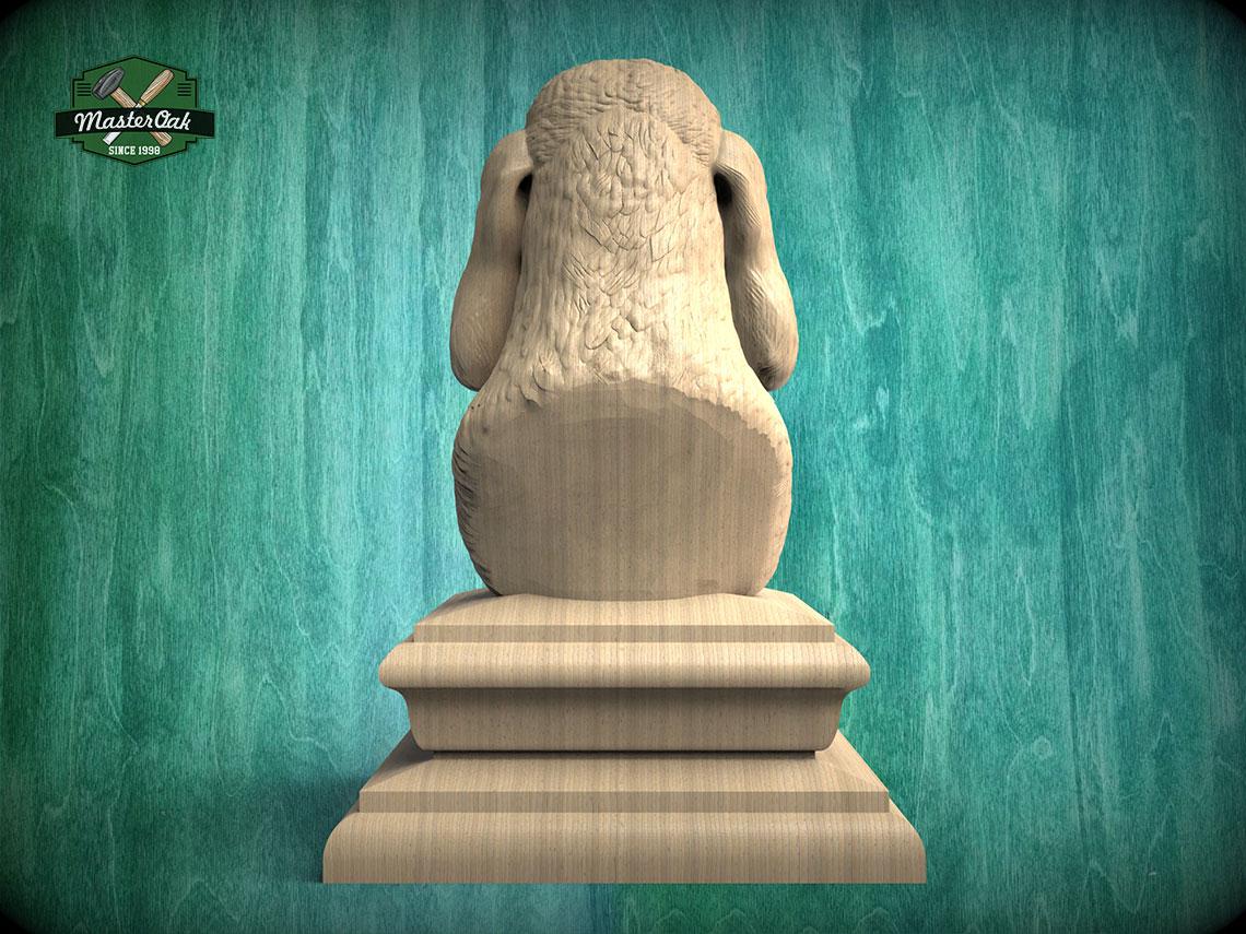 A wooden statue of a monkey sitting on a pedestal against a teal background.