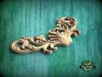A decorative wooden carving with intricate scrollwork is displayed against a green background.