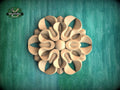 a wooden ornamental piece with a floral design, set against a green background.