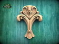 a wooden carving of a stylized flower or plant on a green background.