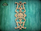 an ornate, carved wooden piece with intricate designs and patterns, mounted on a green wooden surface.