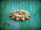 A wooden flower-shaped object is displayed against a green background.