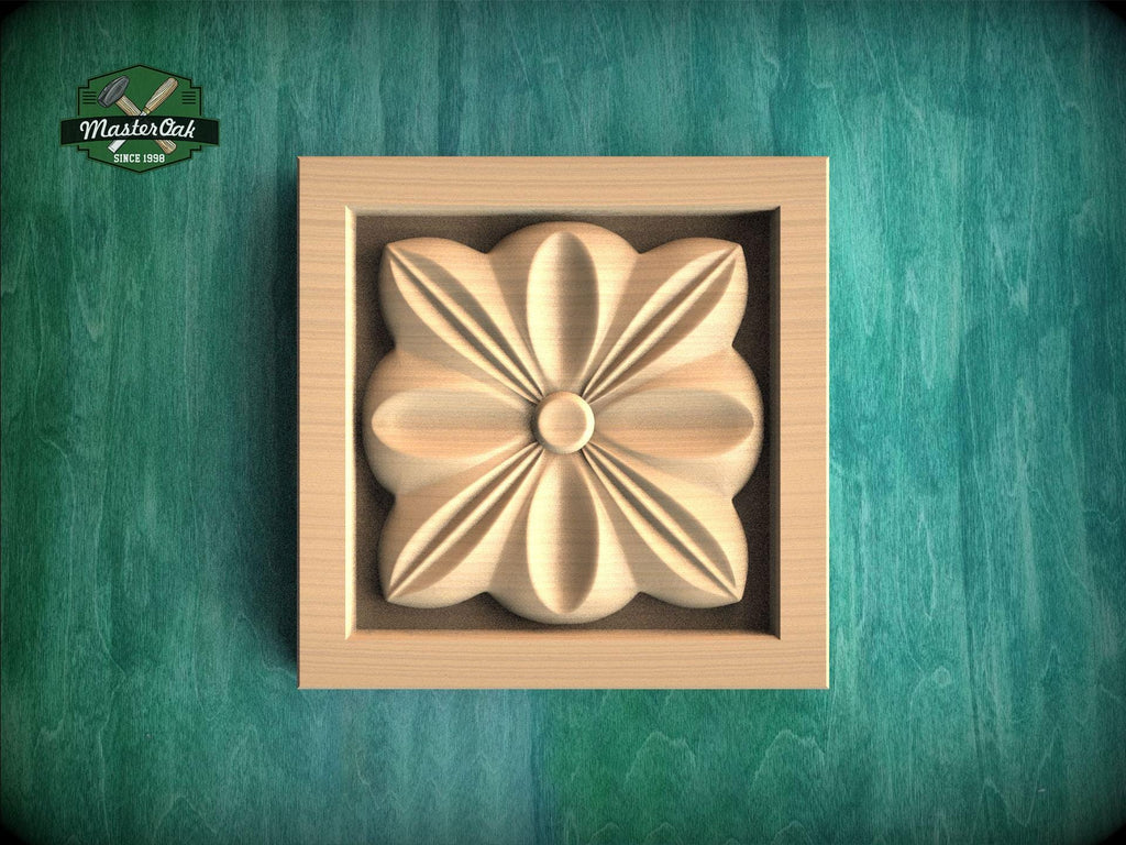 A wooden relief in the shape of a flower is displayed in a square frame against a green background.