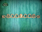 a decorative wooden piece with a floral design, placed against a green background.