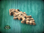 A wooden carving of a flower-like design is displayed against a green background.
