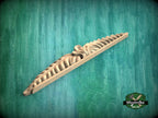 A wooden carving with a decorative design is displayed against a green background.